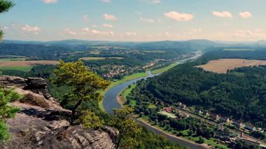 Güneşli bir günde, Elbe Nehri ve küçük bir köyle yeşil vadideki kayalık uçurumdan panoramik manzara. Sakson İsviçre Ulusal Parkı, Almanya 'nın güzel manzarası