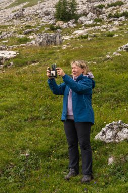 Dolomitlerdeki dağ manzarasını akıllı telefonuyla fotoğraflayan konsantre kadın gezgin. Yürüyüş sırasında doğa anlarını yakalamak. Modern seyahat yaşam tarzı güzel doğada.