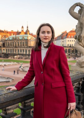 Arkasında Zwinger Sarayı olan tarihi Dresden, Almanya 'yı keşfeden kırmızı paltolu şık Avrupalı kadın. Şehir gezisi, mimari, gezi ve modern yaşam tarzı..