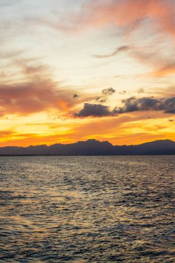 İspanya 'nın Mallorca kentindeki Akdeniz' de, gökyüzünde sıcak renkler ve barışçıl sahil atmosferi yaratan dalgalarla güzel, canlı bir günbatımı..