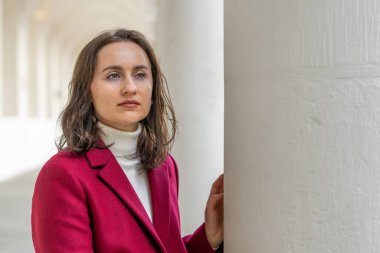 Zarif beyaz sütunlar arasında poz veren çekici kadın modern yaşam tarzıyla şık mimari sahneler yaratıyor..