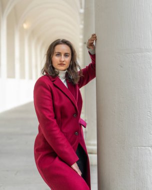 Zarif beyaz sütunlar arasında poz veren çekici kadın modern yaşam tarzıyla şık mimari sahneler yaratıyor..