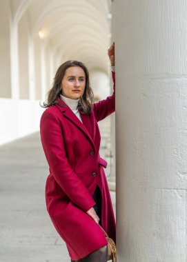 Zarif beyaz sütunlar arasında poz veren çekici kadın modern yaşam tarzıyla şık mimari sahneler yaratıyor..