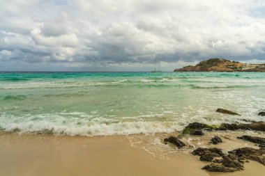 Mallorca, Cala Agulla 'nın açık turkuaz denizinde sürüklenen yat. Rahatlatıcı tatil kavramı, deniz yaşam tarzı, kıyı güzelliği, Akdeniz seyahati.