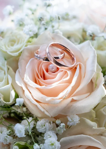 Üstünde alyanslar olan beyaz güllerden yapılmış düğün buketi. Aşkın sembolü, evlilik, bağlılık, düğün töreni.