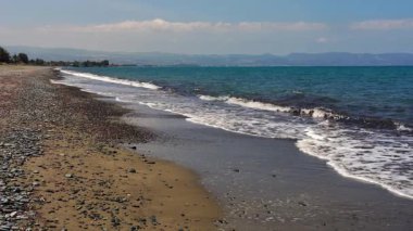 Kıbrıs 'ın güneyindeki çakıl taşlı plajda yumuşak dalgalar koparak sakin bir sahil manzarası yaratıyor. Temiz su, doğal deniz manzarası rahatlama, yaz tatili, huzurlu okyanus titreşimleri..