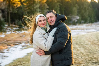 Kışın açık havada, gülen adam ve kadın portresi. Çift soğuk havada ve temiz havada bir anı paylaşıyor.