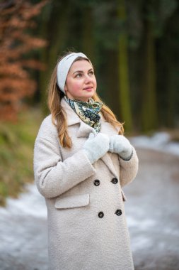 Sıcak kışlık giysiler içinde mutlu bir kadın kış ormanında dışarıda vakit geçiriyor. Gülümseyen dişi dışarıda eğleniyor, soğuk hava ve aktif kış yaşam tarzı, doğal güzellik..