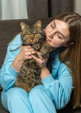 Çizgili kedisini evde tutan kadının yakın plan portresi. Hayvan bakımı, şefkat, rahatlık ve arkadaşlık kavramı.