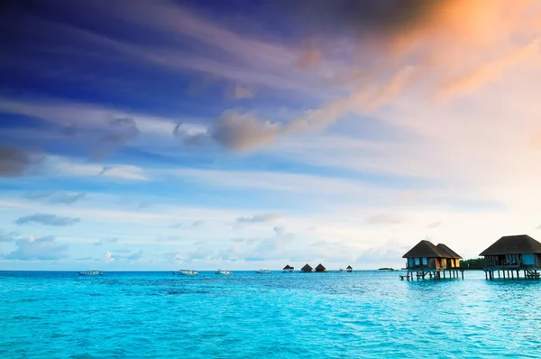 Salida del sol sobre bungalows de agua en Maldivas — Foto de Stock