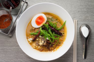 Sığır şehriye çorba kasesi ile ahşap bir zemin üzerinde beyaz.