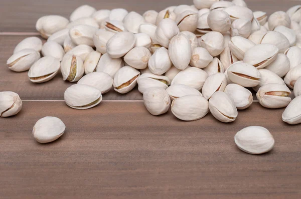 Pistachos asados y salados en cáscara sobre fondo de madera — Foto de Stock