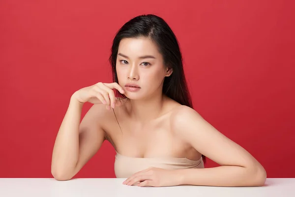 Güzel genç Asyalı kadın, kırmızı arka planda temiz ten, yüz bakımı, yüz bakımı, kozmetoloji, güzellik ve kaplıca, Asyalı kadın portresi..