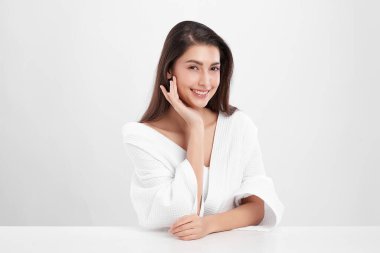 Beyaz arkaplanda bornoz, yüz bakımı, yüz bakımı, kozmetoloji, güzellik ve spa konsepti olan güzel Asyalı bir kadın..