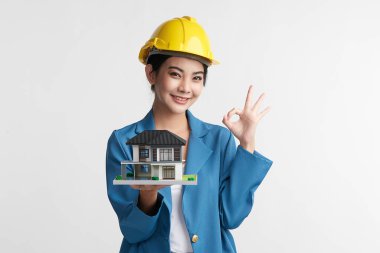 Güzel Asyalı kadın mühendis elinde beyaz arka plan, inşaat konsepti, mühendis, endüstri üzerine ev modelini gösteriyor..