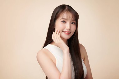 Güzel, genç bir Asyalı kadın, bej bir arka planda temiz, taze bir ten. Cilt bakımı, yüz bakımı, kozmetoloji, güzellik ve kaplıca. Asyalı bir kadının zarif bir portresi..