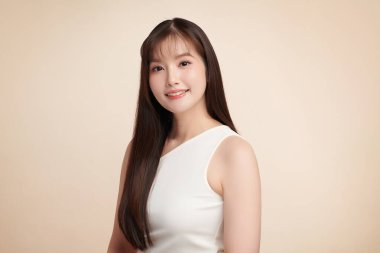 Güzel, genç bir Asyalı kadın, bej bir arka planda temiz, taze bir ten. Cilt bakımı, yüz bakımı, kozmetoloji, güzellik ve kaplıca. Asyalı bir kadının zarif bir portresi..