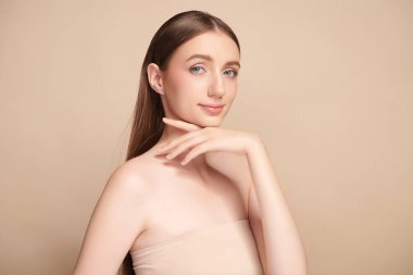 Bej bir arka planda temiz, taze bir teni olan güzel bir genç kadın. Cilt bakımı, yüz bakımı, kozmetoloji, güzellik ve kaplıca. Bir kadının zarif bir portresi..