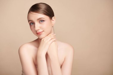 Bej bir arka planda temiz, taze bir teni olan güzel bir genç kadın. Cilt bakımı, yüz bakımı, kozmetoloji, güzellik ve kaplıca. Bir kadının zarif bir portresi..