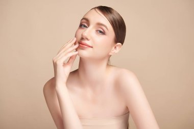 Bej bir arka planda temiz, taze bir teni olan güzel bir genç kadın. Cilt bakımı, yüz bakımı, kozmetoloji, güzellik ve kaplıca. Bir kadının zarif bir portresi..