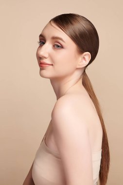 Bej bir arka planda temiz, taze bir teni olan güzel bir genç kadın. Cilt bakımı, yüz bakımı, kozmetoloji, güzellik ve kaplıca. Bir kadının zarif bir portresi..