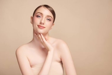 Bej bir arka planda temiz, taze bir teni olan güzel bir genç kadın. Cilt bakımı, yüz bakımı, kozmetoloji, güzellik ve kaplıca. Bir kadının zarif bir portresi..