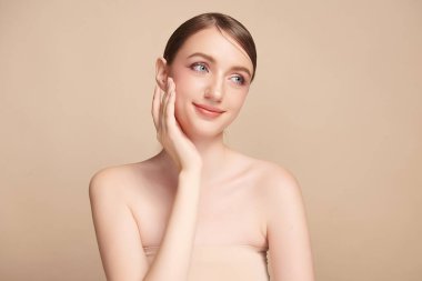 Bej bir arka planda temiz, taze bir teni olan güzel bir genç kadın. Cilt bakımı, yüz bakımı, kozmetoloji, güzellik ve kaplıca. Bir kadının zarif bir portresi..