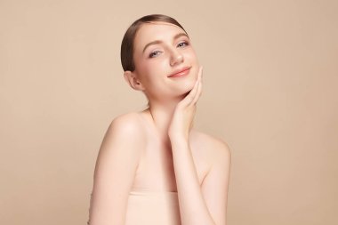 Bej bir arka planda temiz, taze bir teni olan güzel bir genç kadın. Cilt bakımı, yüz bakımı, kozmetoloji, güzellik ve kaplıca. Bir kadının zarif bir portresi..