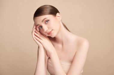 Bej bir arka planda temiz, taze bir teni olan güzel bir genç kadın. Cilt bakımı, yüz bakımı, kozmetoloji, güzellik ve kaplıca. Bir kadının zarif bir portresi..