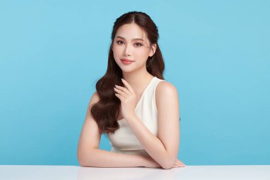 Güzel, genç bir Asyalı kadın, temiz, taze bir cilde sahip, mavi bir arka planda. Cilt bakımı, yüz bakımı, kozmetoloji, güzellik ve kaplıca. Asyalı bir kadının zarif bir portresi..