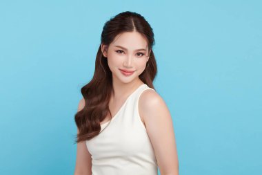 Güzel, genç bir Asyalı kadın, temiz, taze bir cilde sahip, mavi bir arka planda. Cilt bakımı, yüz bakımı, kozmetoloji, güzellik ve kaplıca. Asyalı bir kadının zarif bir portresi..