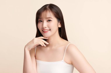 Güzel, genç bir Asyalı kadın, bej bir arka planda temiz, taze bir ten. Cilt bakımı, yüz bakımı, kozmetoloji, güzellik ve kaplıca. Asyalı bir kadının zarif bir portresi..