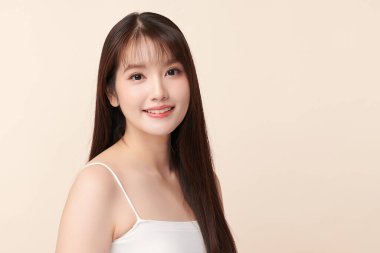 Güzel, genç bir Asyalı kadın, bej bir arka planda temiz, taze bir ten. Cilt bakımı, yüz bakımı, kozmetoloji, güzellik ve kaplıca. Asyalı bir kadının zarif bir portresi..