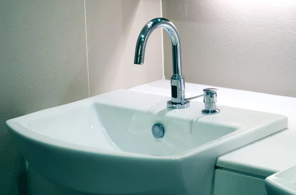 Wasserhahn mit weißem Waschbecken mit Keramikfliesen Hintergrund — Stockfoto