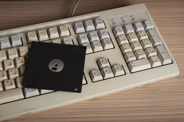 Un teclado viejo en un escritorio con un disquete — Foto de Stock