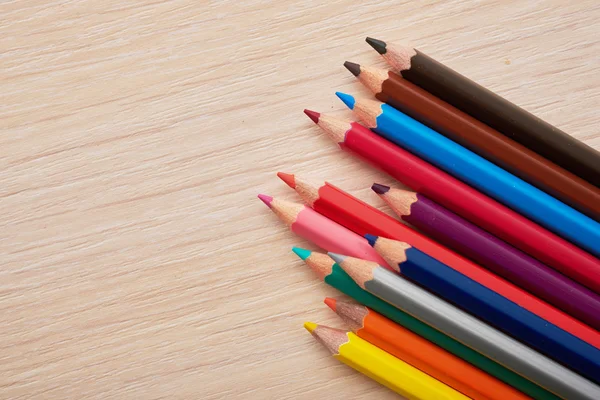 Lápices de colores acostados en un escritorio de madera — Foto de Stock