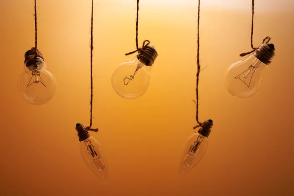 Cinque lampadine ad incandescenza su sfondo arancione — Foto Stock