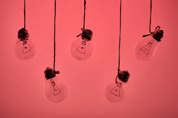 Cinque lampadine ad incandescenza appese su fondo rosa — Foto Stock