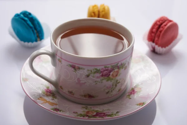 Макарун и чай на белом фоне — стоковое фото
