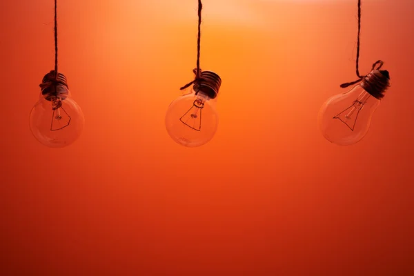 Tre lampade ad incandescenza su fondo rosso — Foto Stock