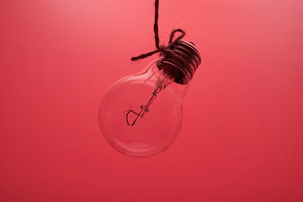 Una lampada ad incandescenza su fondo rosso — Foto Stock