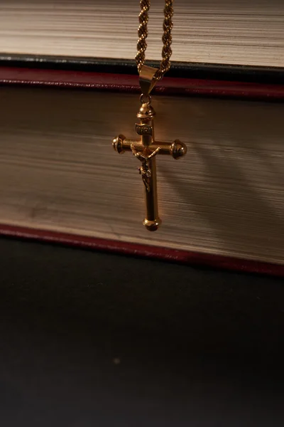 Kříž na řetízku visící na pozadí knihy — Stock fotografie