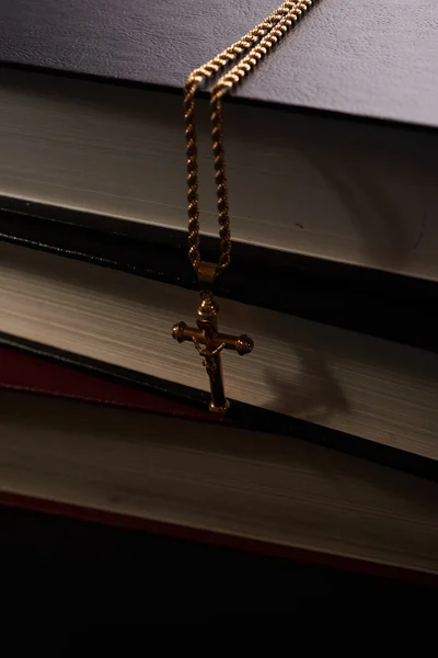 Goldkreuz an einer Kette, die an Hintergrundbüchern hängt — Stockfoto