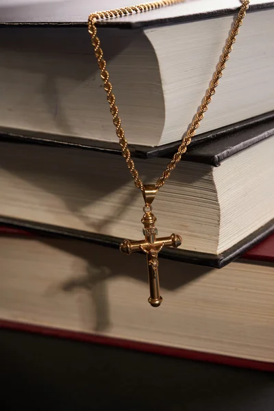 Krzyż wiszący na tle książek — Zdjęcie stockowe