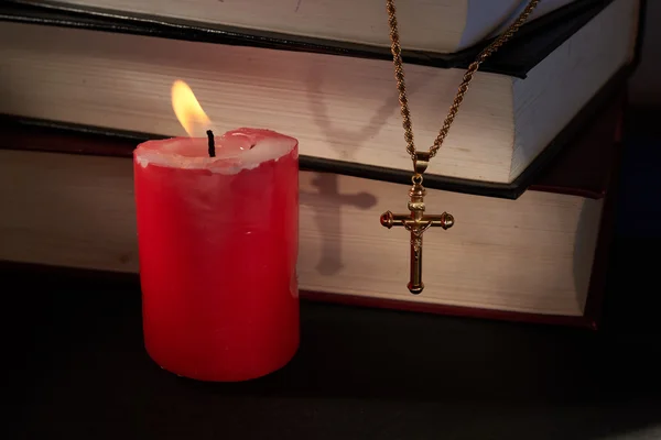 Kreuz, brennende Kerzen und Bücher — Stockfoto