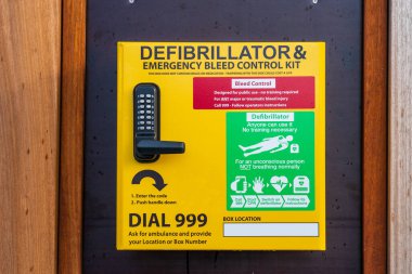 İnşaat alanındaki bir çitin üzerindeki acil durum defibrilatörü, sağlık ve güvenlikle ilgili teknoloji cihazı