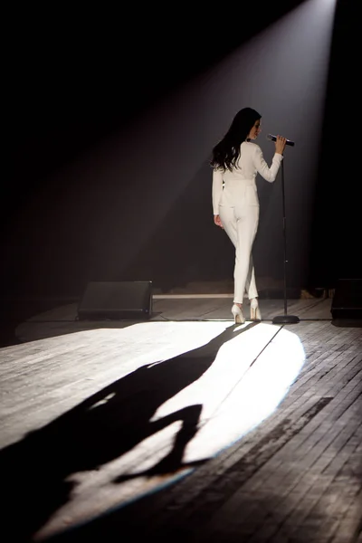 Singer on stage in a beam of white light.