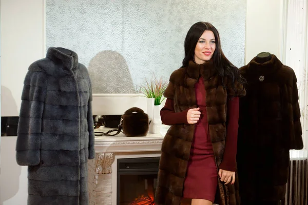 Luxury clothing concept. Woman with fur coat. Girl in a fur coat coat in shop with fur on background.
