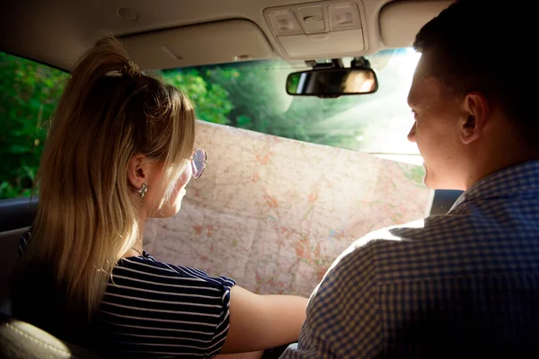 Happy couple with map in car. Smiling man and woman using a map on the road.