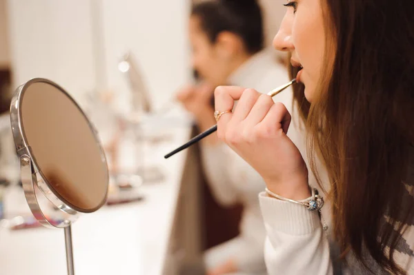 School of makeup. Make up artist doing professional make up of young woman.